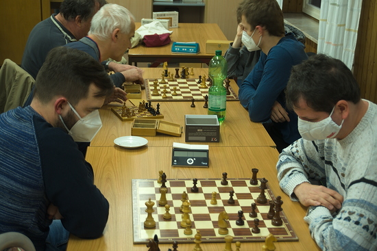 Szene vom Vereinsabend, an der Tischreihe sitzen sich Schachspieler gegenüber 